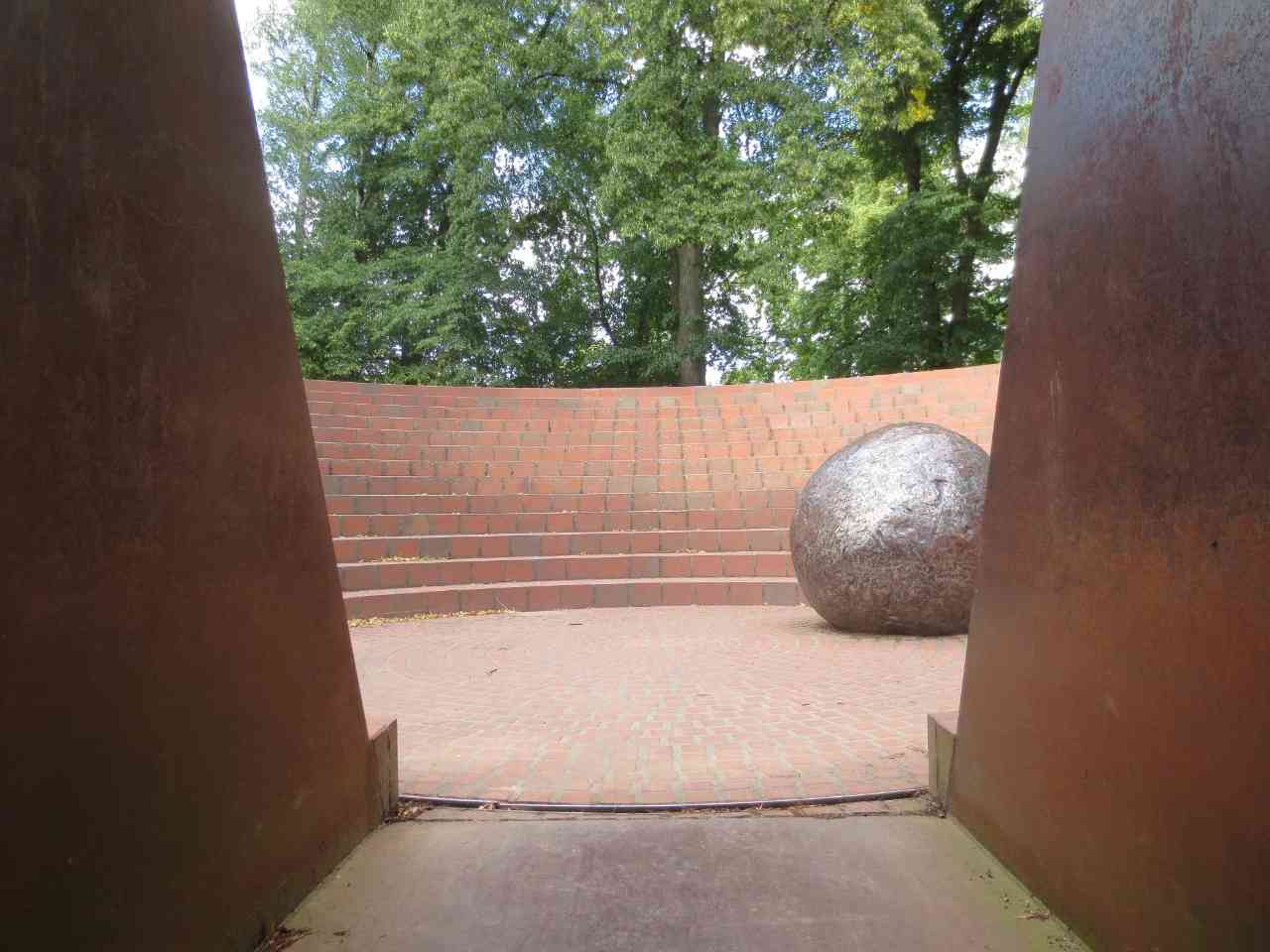 Blick ins Denkmal, Gedenken, durch den Tunnel, Amphitheater ähnliches Kreis aus Backsteinen und Metall, große Metallkugel in der Mitte