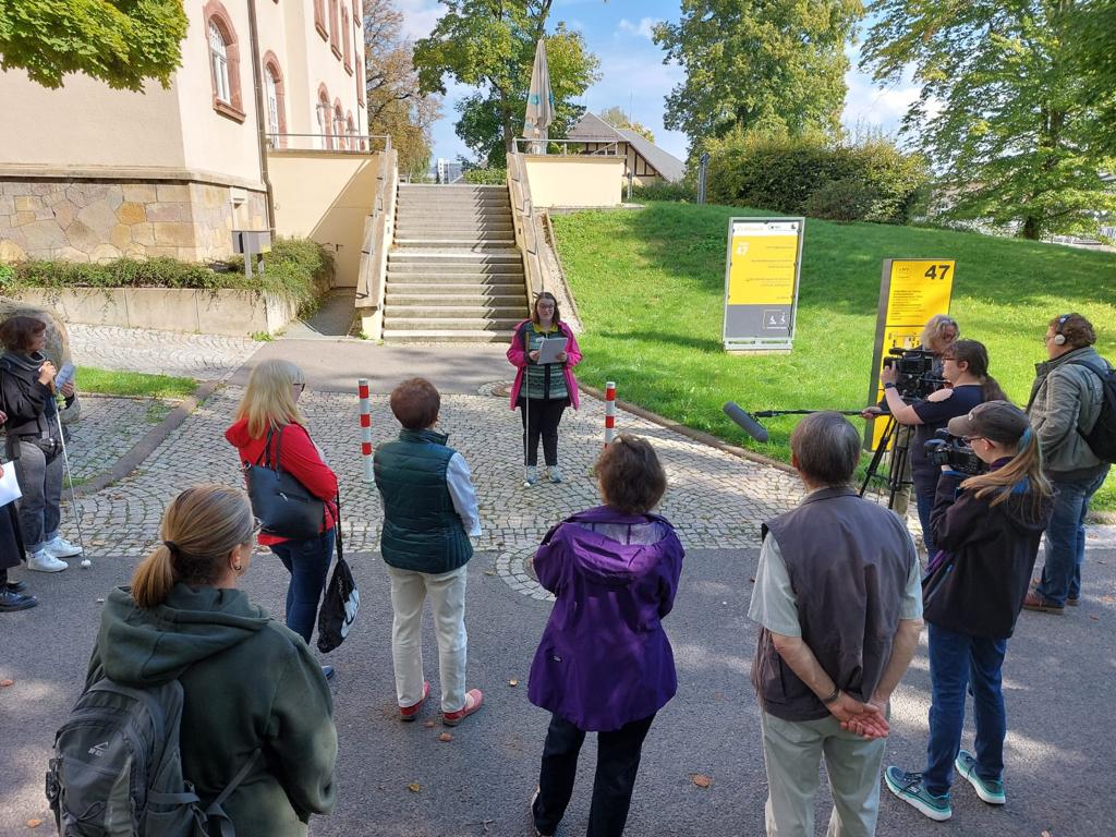 Gruppe von Menschen auf Straße vor Treppe mit Wiese, Haus 47