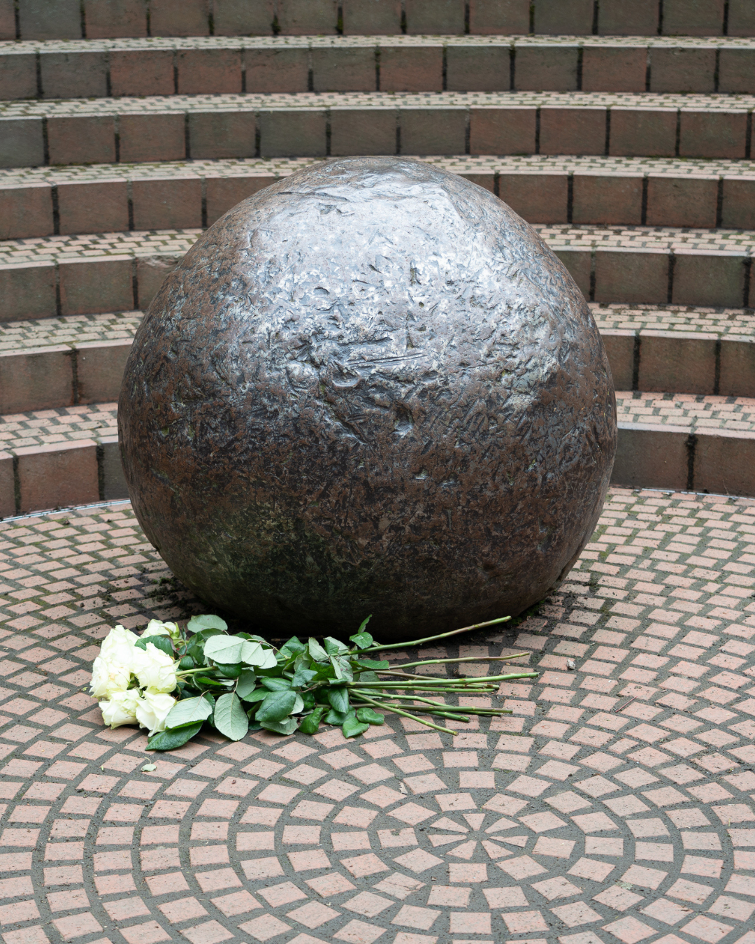 Das Denkmal GEDENKEN mit niedergelegten weißen Rosen.