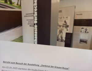Im Vordergrund ist die Überschrift eines Berichts zu sehen. Dahinter kann man schemenhaft die Ausstellung erkennen.