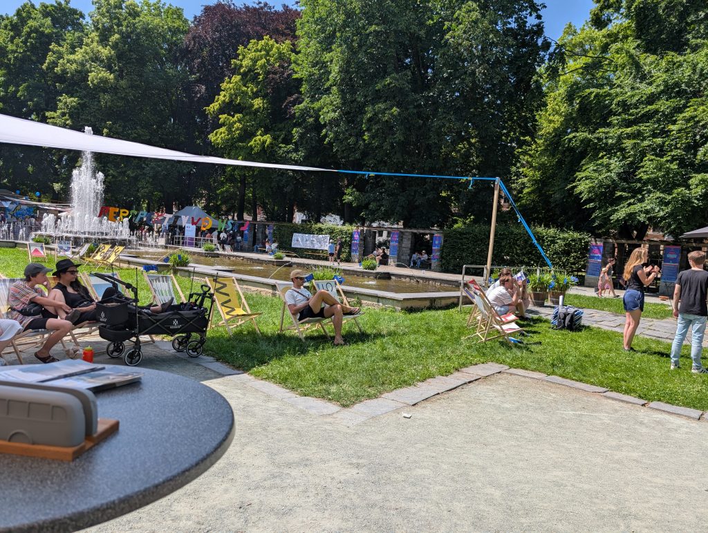 Die Oase am Brunnen - Liegestühle stehen auf den Flächen rund um den Brunnen. Es gibt Plätze in der Sonne und im Schatten.