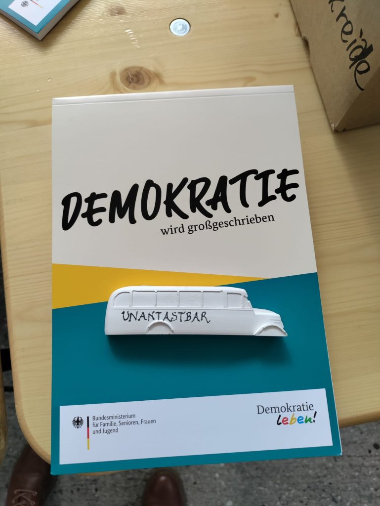 Ein mit dem Wort "Unantastbar" beschriebenes Gipsmodell des Denkmals der Grauen Busse auf einer Unterlage mit der Aufschrift "Demokratie wird großgeschrieben".